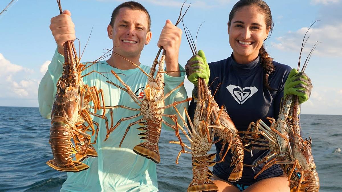 Young couple show off 7 lobsters on their sailboat